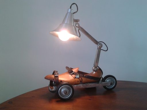 Smooth (im)mobilty n°1 Lampe à posée faite d'un Embauchoir monté sur patin à roulette 3 roues surmonté d'une lampe vintage de type industriel.