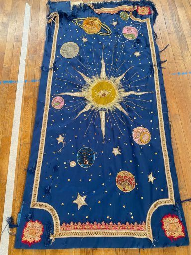 La Boîte magique de la Fée Tenture bleu rois avec soleil doré et planètes réalisées à partir de textiles de seconde main issu d'un vide maison.